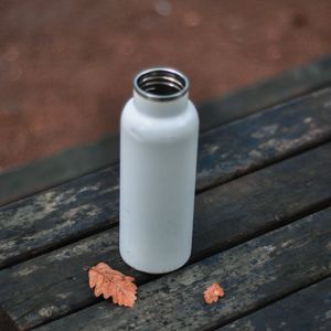 Metal water bottle sitting on a bench.