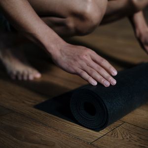 Rolled up yoga mat on a wooden floor.